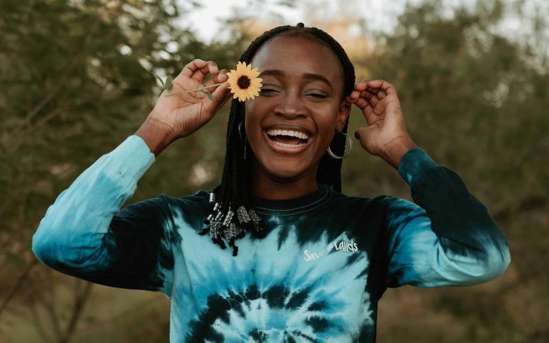 woman holds a flower in her hair in a park