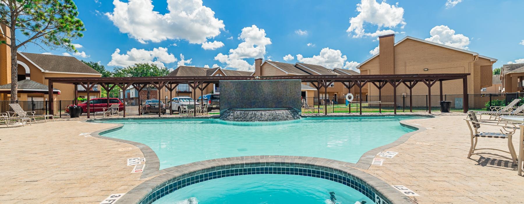 a pool in a sandy area with buildings in the background